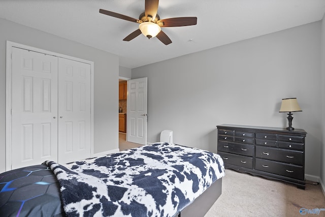 bedroom with light carpet, ceiling fan, and a closet