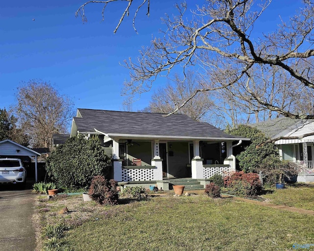 bungalow-style house featuring a front yard, driveway, a porch, a shingled roof, and a carport