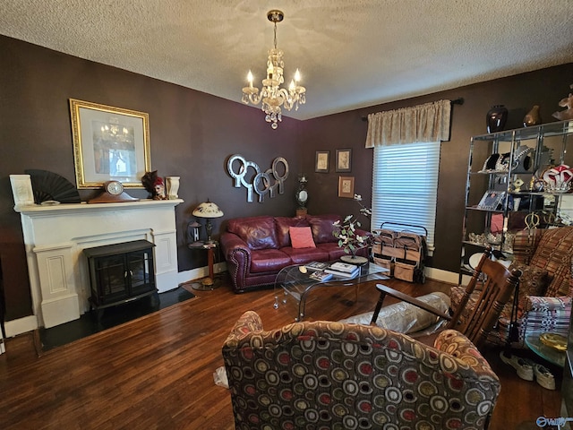 living area with baseboards, a chandelier, wood finished floors, a glass covered fireplace, and a textured ceiling