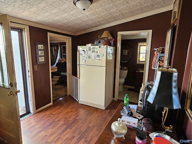 interior space with baseboards, wood finished floors, ornamental molding, and freestanding refrigerator