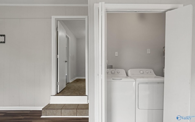 laundry area featuring wood walls, washer and dryer, and dark hardwood / wood-style floors