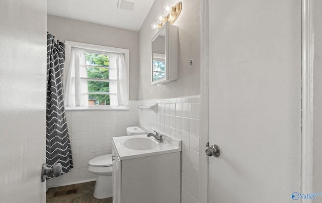 bathroom with curtained shower, tile patterned floors, toilet, vanity, and tile walls