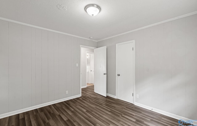 empty room with a textured ceiling, dark hardwood / wood-style floors, wood walls, and crown molding