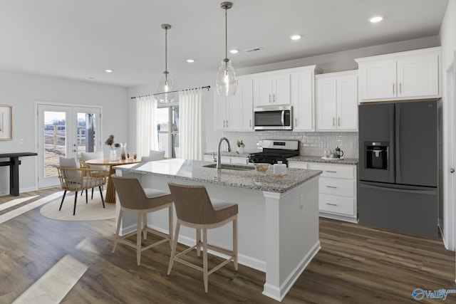 kitchen with sink, white cabinetry, hanging light fixtures, a center island with sink, and appliances with stainless steel finishes