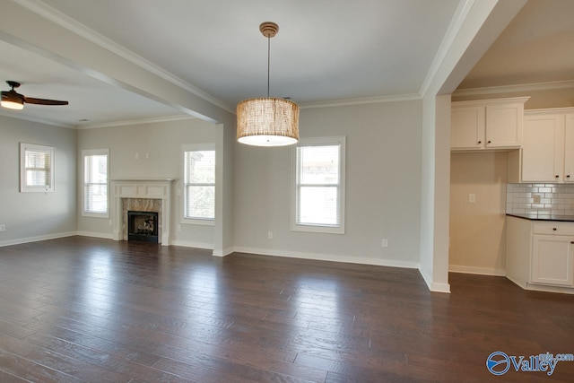 unfurnished living room with dark wood finished floors, baseboards, a ceiling fan, and a fireplace