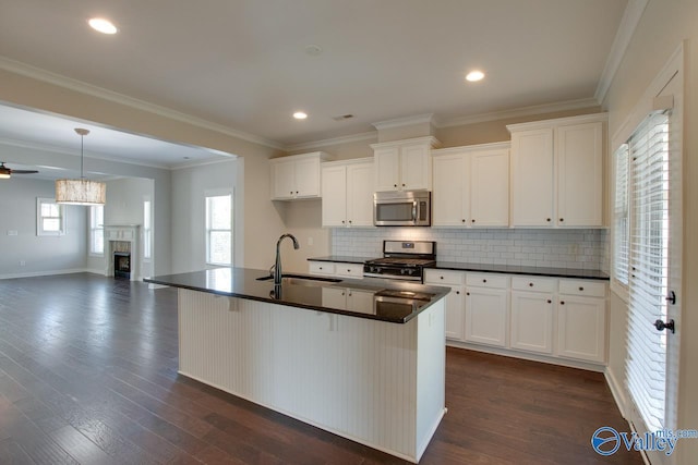kitchen featuring dark wood finished floors, dark countertops, appliances with stainless steel finishes, and a sink