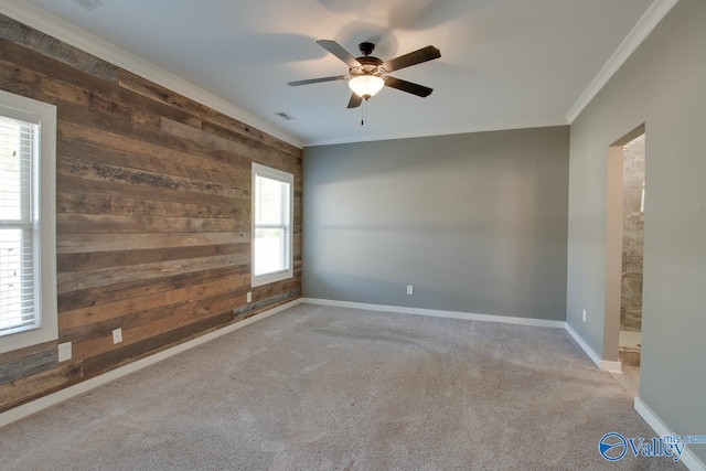 unfurnished room with wood walls, visible vents, a ceiling fan, ornamental molding, and carpet floors