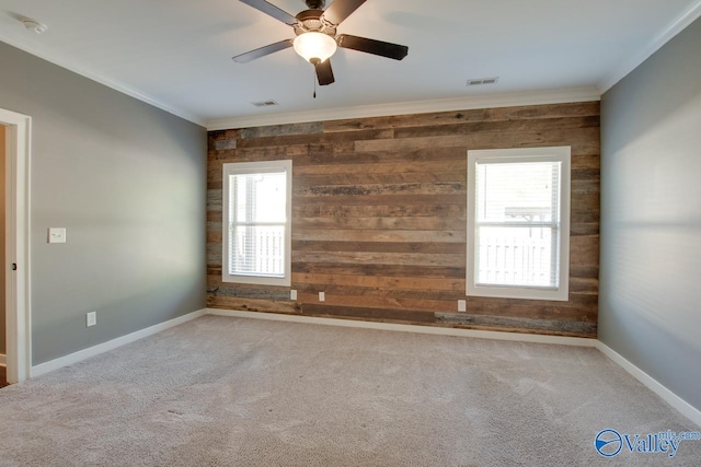 carpeted spare room with wood walls, ornamental molding, and visible vents