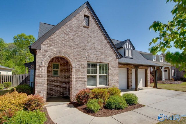 view of front of house with roof with shingles, driveway, fence, brick siding, and an attached garage