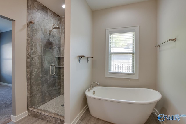 full bathroom with baseboards, a shower stall, and a freestanding bath