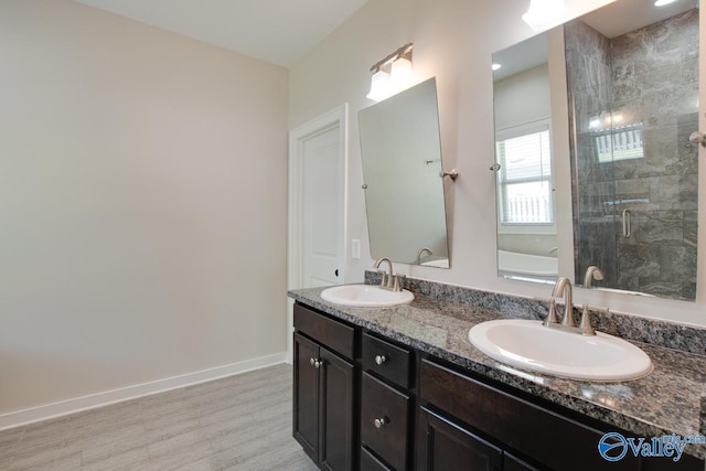 full bathroom with baseboards, wood finished floors, a sink, and a stall shower