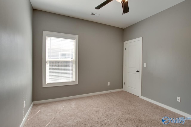 carpeted spare room with baseboards, visible vents, and ceiling fan