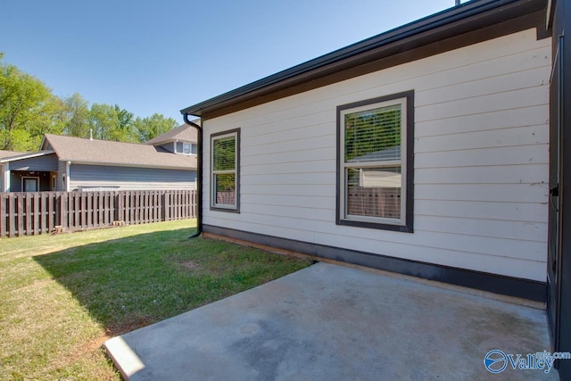 view of side of home featuring fence, a yard, and a patio