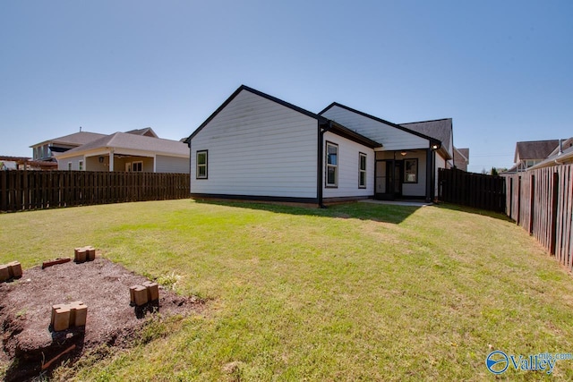 rear view of house with a yard and a fenced backyard
