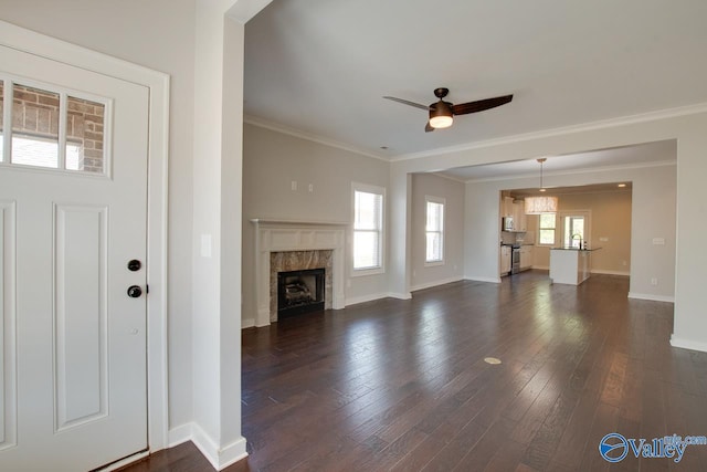 unfurnished living room featuring dark wood-style flooring, a ceiling fan, a premium fireplace, and plenty of natural light