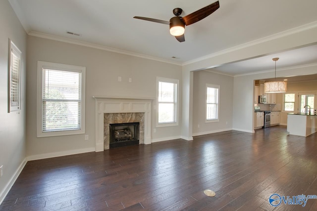 unfurnished living room with a premium fireplace, a sink, ceiling fan, and dark wood-style flooring