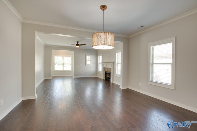 unfurnished living room with baseboards, ceiling fan, a fireplace, dark wood-type flooring, and ornamental molding