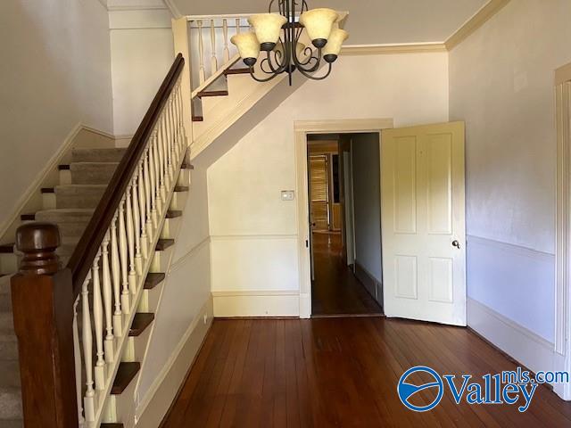 stairway with crown molding, hardwood / wood-style flooring, and a chandelier