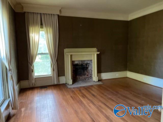 unfurnished living room with hardwood / wood-style floors and crown molding