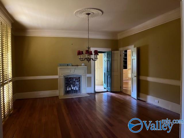 unfurnished living room with an inviting chandelier, ornamental molding, and hardwood / wood-style floors