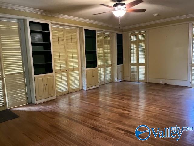 empty room featuring crown molding, built in shelves, and hardwood / wood-style floors