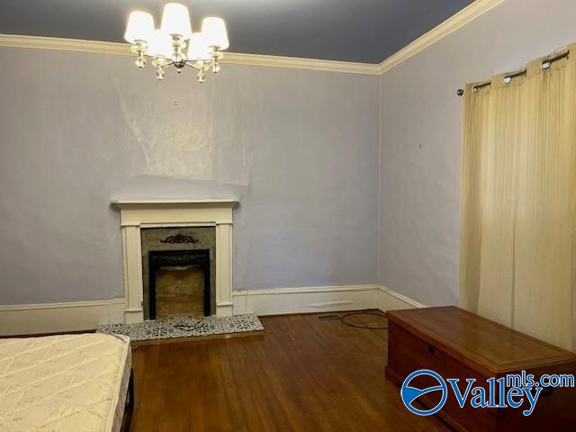 unfurnished living room with wood-type flooring, a notable chandelier, and crown molding