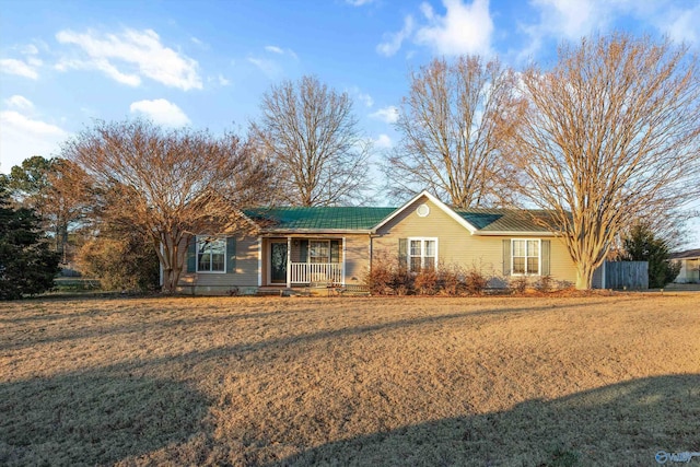 ranch-style home featuring covered porch and a front lawn