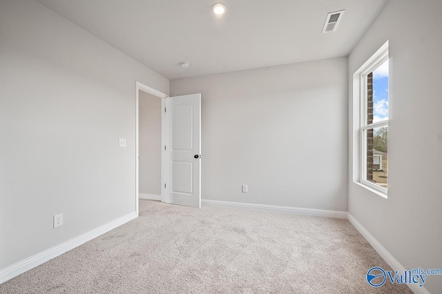 carpeted spare room featuring visible vents and baseboards