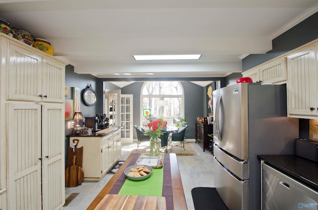 kitchen with cream cabinetry, lofted ceiling with beams, dark countertops, and appliances with stainless steel finishes