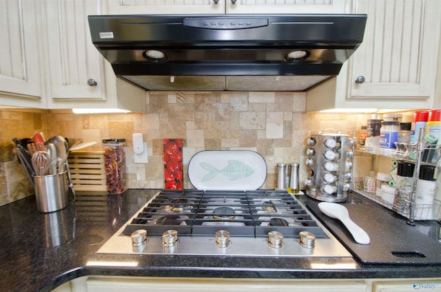 kitchen with decorative backsplash, under cabinet range hood, dark countertops, and stainless steel gas stovetop