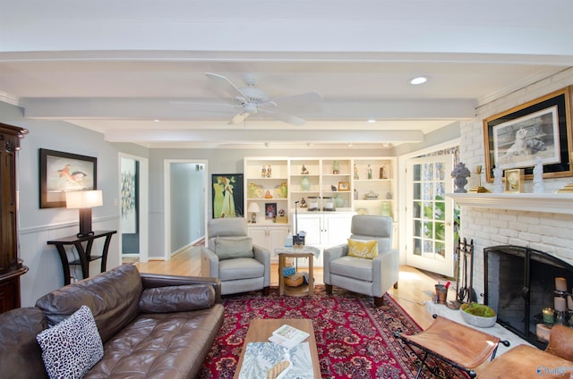 living room featuring a fireplace, wood finished floors, ceiling fan, and beam ceiling