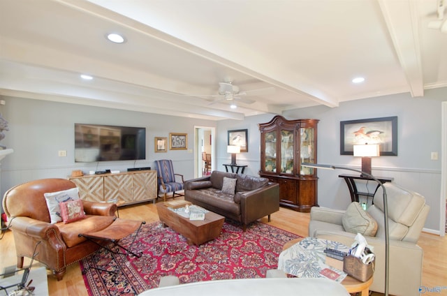 living area with beamed ceiling, wainscoting, light wood-style floors, and a ceiling fan