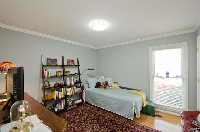 bedroom featuring visible vents, ornamental molding, and wood finished floors