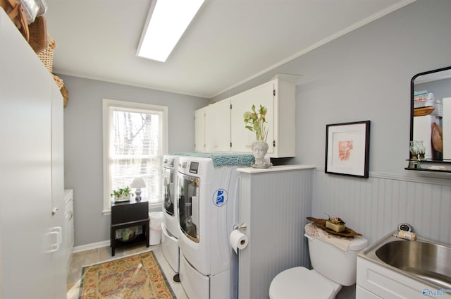 laundry area featuring light tile patterned flooring, a sink, washing machine and dryer, laundry area, and wainscoting