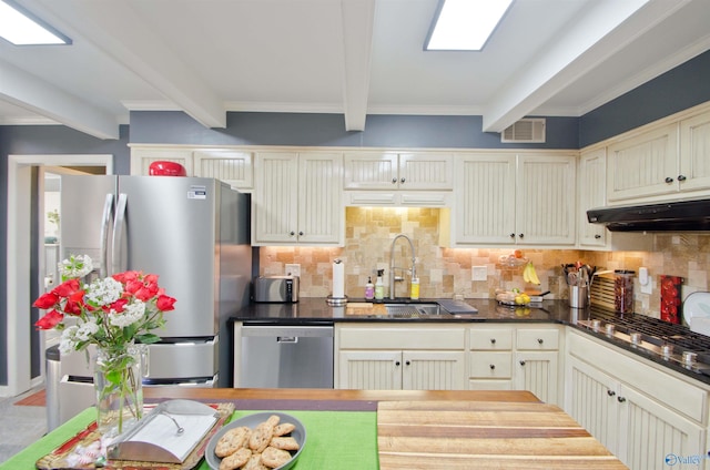 kitchen featuring tasteful backsplash, stainless steel appliances, under cabinet range hood, beamed ceiling, and visible vents