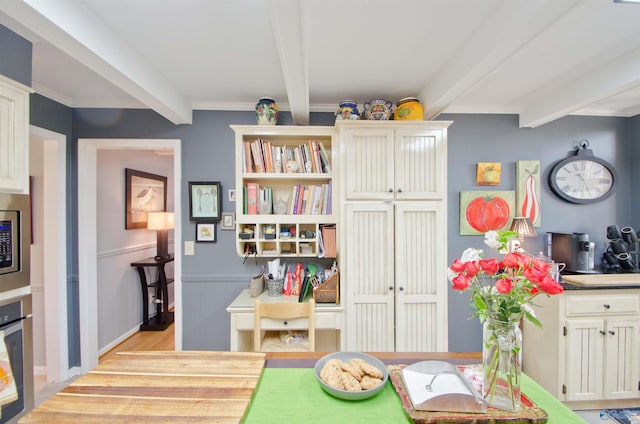 playroom with light wood-style flooring, beamed ceiling, and wainscoting