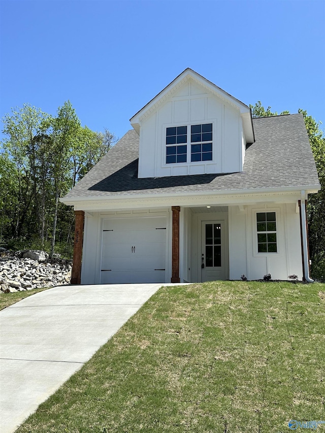 view of front of house with board and batten siding, a front yard, driveway, and roof with shingles