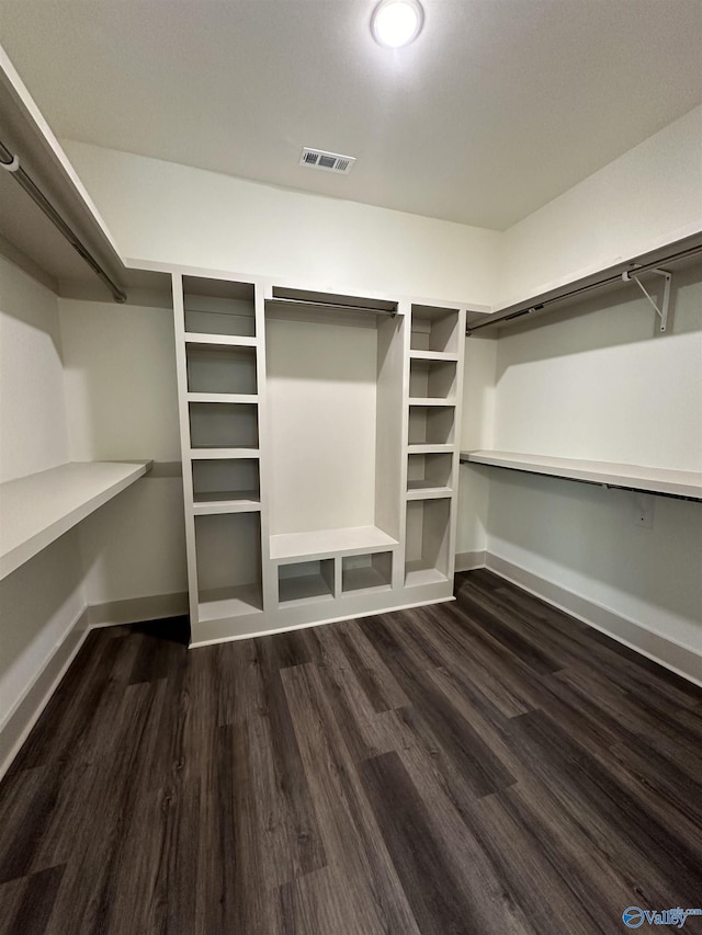 walk in closet with dark wood finished floors and visible vents