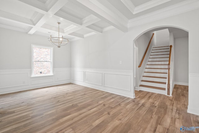 unfurnished room with coffered ceiling, beam ceiling, crown molding, a chandelier, and light hardwood / wood-style floors