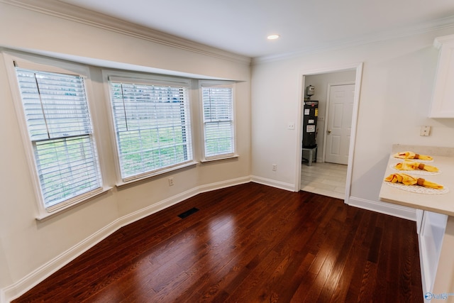 unfurnished dining area featuring ornamental molding and dark hardwood / wood-style flooring