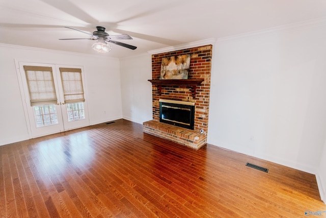 unfurnished living room featuring ornamental molding, hardwood / wood-style floors, and a brick fireplace