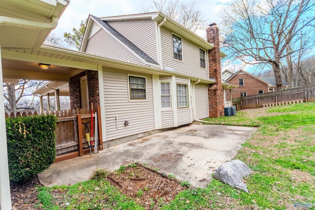 rear view of house featuring central AC unit, a yard, and a patio area