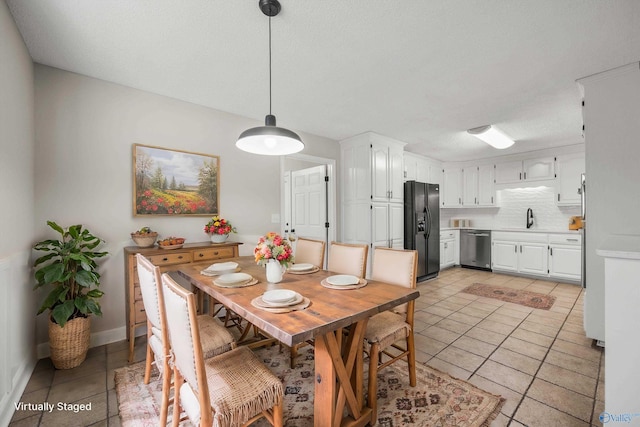 dining space featuring a textured ceiling, light tile patterned floors, and sink