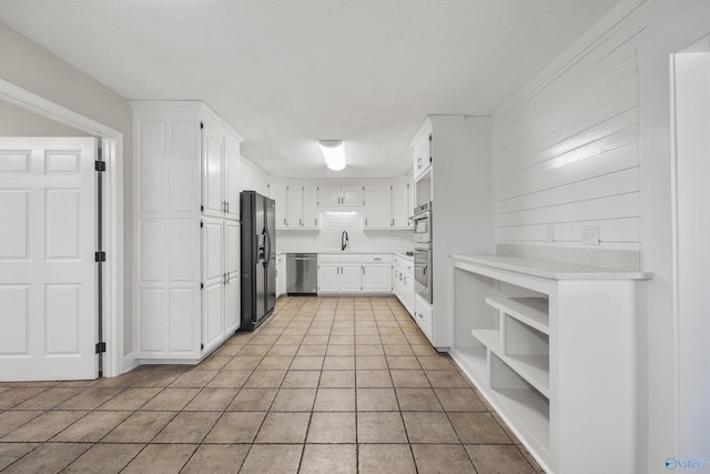 kitchen featuring white cabinets, appliances with stainless steel finishes, light tile patterned flooring, and sink