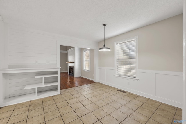 unfurnished dining area featuring light tile patterned floors and a textured ceiling
