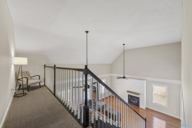 hall with a textured ceiling, hardwood / wood-style floors, and vaulted ceiling