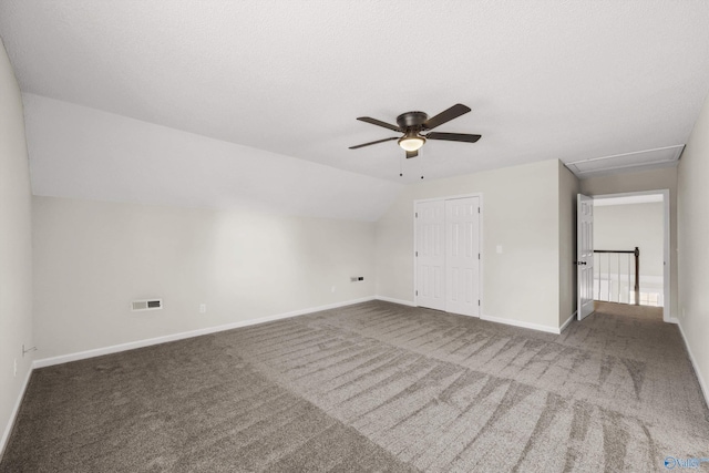 interior space featuring ceiling fan, a closet, dark carpet, and lofted ceiling