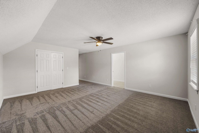 additional living space with a textured ceiling, dark carpet, ceiling fan, and lofted ceiling