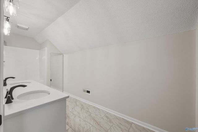 bathroom with a textured ceiling, a shower, vanity, and lofted ceiling