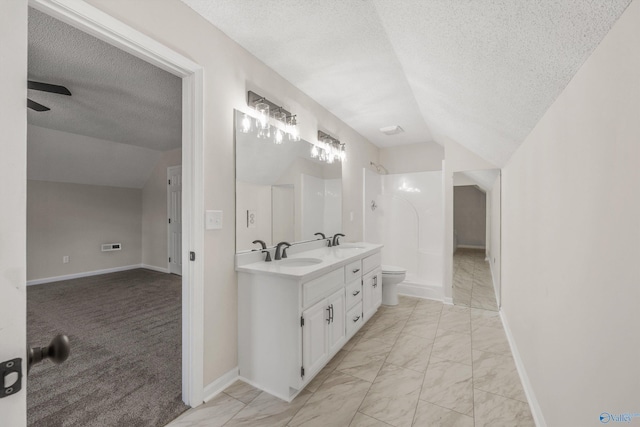 bathroom featuring ceiling fan, a textured ceiling, lofted ceiling, toilet, and vanity